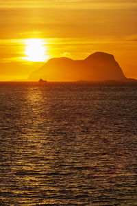 Seascape view at a rock in sunset with a fishing boa