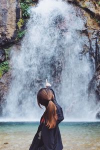 Rear view of woman looking at waterfall