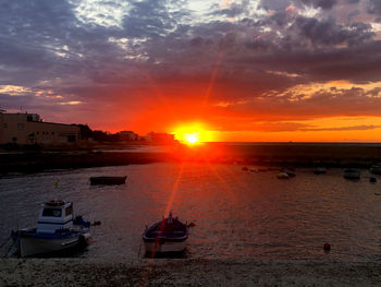 Sailboats moored on sea against sky during sunset