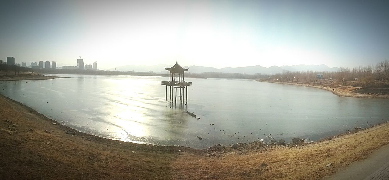 water, built structure, architecture, building exterior, clear sky, reflection, river, sky, copy space, city, travel destinations, outdoors, famous place, sunlight, day, no people, bridge - man made structure, pier, travel, tourism