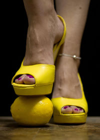 Low section of woman standing over lemon