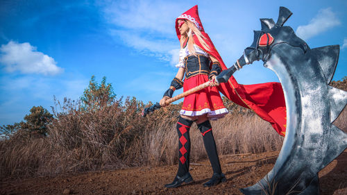 Low angle view of young woman in halloween costume while standing on field against sky