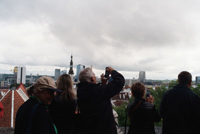 Rear view of people photographing against sky