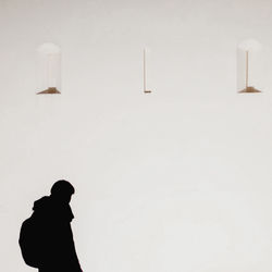 Silhouette man standing against wall