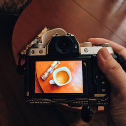 Cropped image of person taking photograph of cup indoors