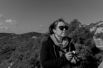 Woman wearing sunglasses standing against sky