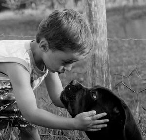 Close-up of boy holding dog while standing on field