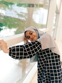 Portrait of woman standing against window