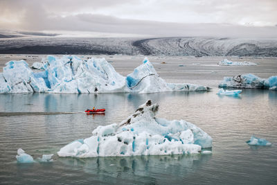 Icebergs in frozen sea against sky