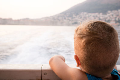 Small boy on cruising ship looking at the view from a deck and enjoying in summer day.