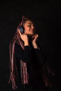 Young woman looking away against black background