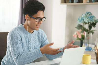 Young man using mobile phone while sitting on table