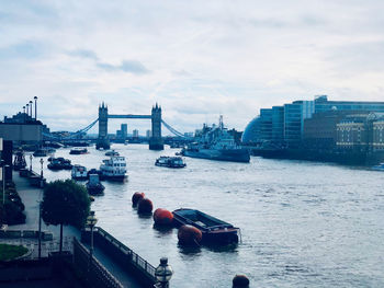 Boats in river against sky in city