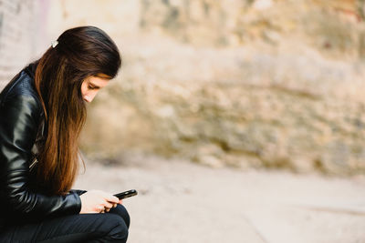 Side view of woman using mobile phone outdoors