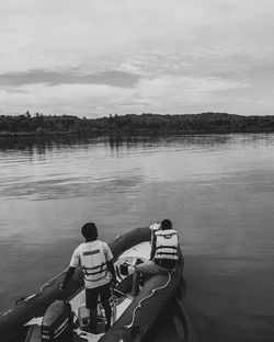 Rear view of people in lake against sky