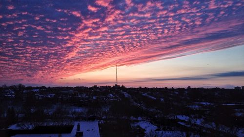 Scenic view of landscape against cloudy sky at sunset