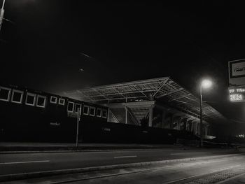 Road by illuminated city against sky at night