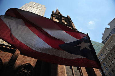 Low angle view of cuban flag waving against buildings and church