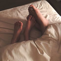 Low section of couple lying on bed