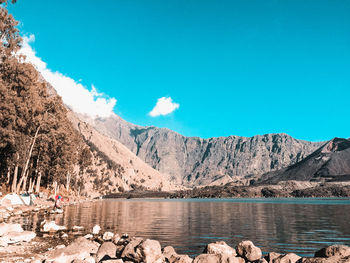 Scenic view of lake and mountains against blue sky