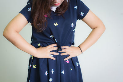 Midsection of woman suffering from stomachache against white background