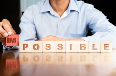 Midsection of businessman with impossible text on toy blocks at desk