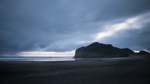 Scenic view of beach against sky at dusk