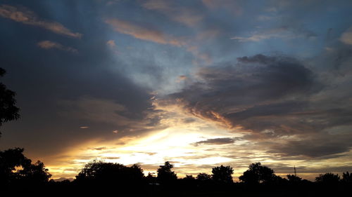 Low angle view of silhouette trees against dramatic sky