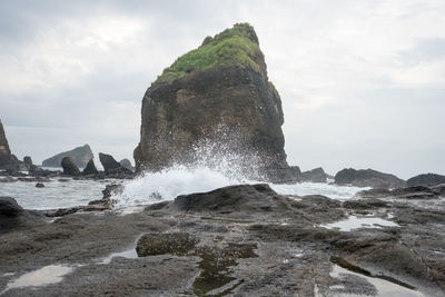 Sea waves splashing on shore against sky