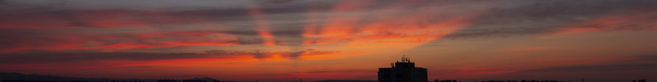 Silhouette of building against cloudy sky at sunset