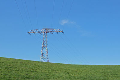 Low angle view of electricity pylon on field against sky