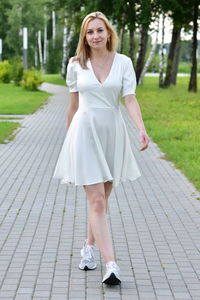 Portrait of young woman standing on footpath