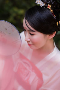 Woman in traditional clothing holding hand fan outdoors