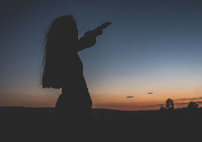 Silhouette woman standing against sky during sunset