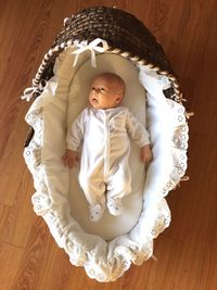 Directly above view of baby in wicker baby carriage on hardwood floor