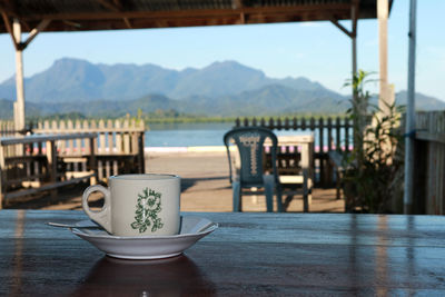 Coffee cup on table by mountains against sky