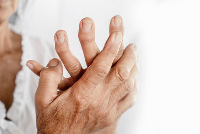 Close-up of hand holding hands over white background