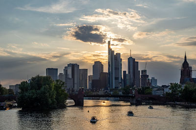 City at waterfront against sky during sunset