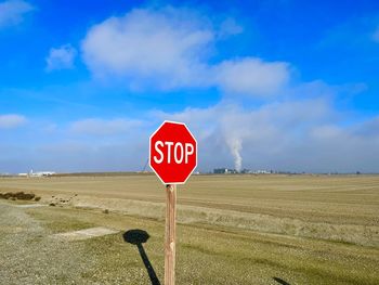 Road sign on field against sky