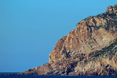 Low angle view of rock formation against clear blue sky