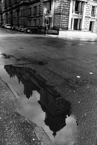 Reflection of building in puddle on road