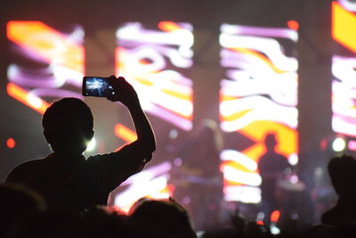 Silhouette man photographing at music concert