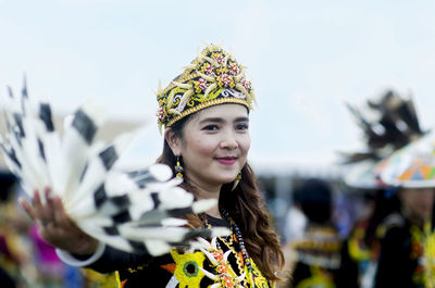 Smiling young woman wearing traditional clothing against sky