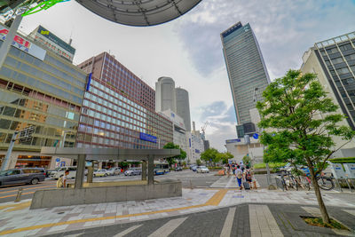 City street by modern buildings against sky