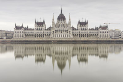 Reflection of building by river with city in background