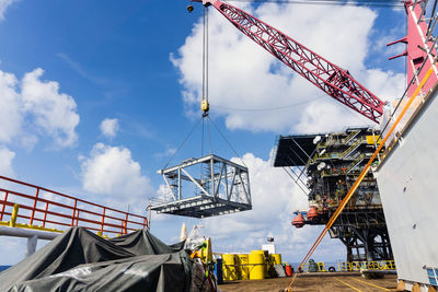 Low angle view of crane at construction site against sky