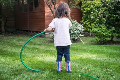 Rear view of toddler watering the garden 