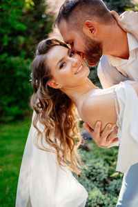 Newlywed couple embracing while standing outdoors