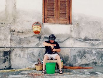 Rear view of woman sitting on wall