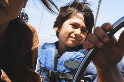 Boy wearing life jacket while traveling in sailboat with parents